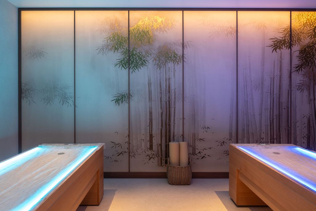 Spa therapy room featuring soft lighting, massage bed, and calming neutral tones.