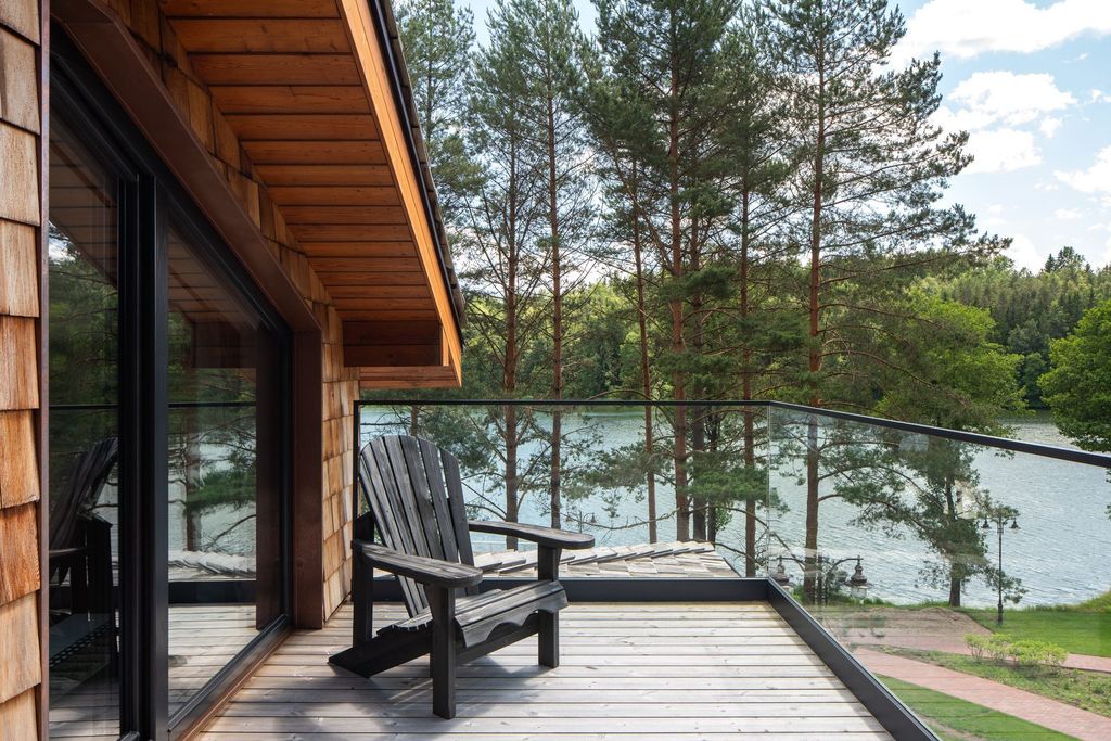 Loft suite living area opening to a terrace with serene forest and lake view.